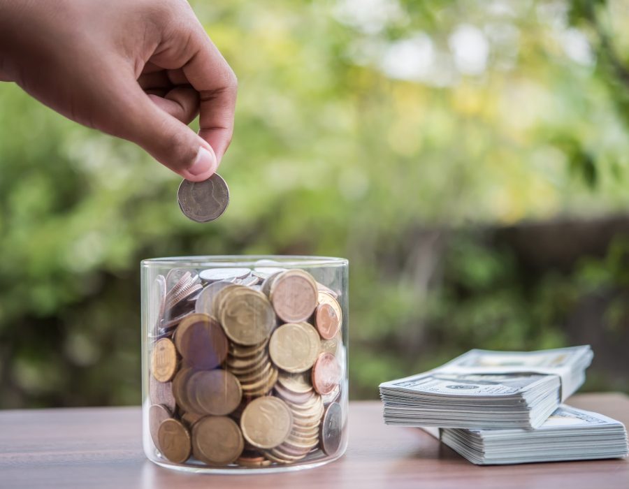 Hand putting coins in jar with money stack step growing growth saving money